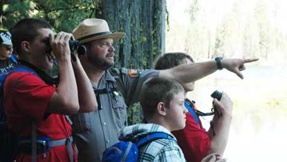 Students and a park ranger spot a bird at Manzanita Lake. 