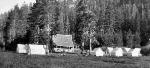 small white guest tents in meadow with lodge