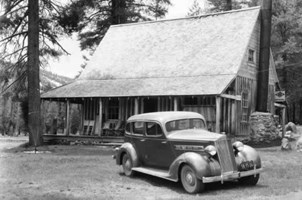 b/w picture of 1935 packard automobile in front of rustic lodge