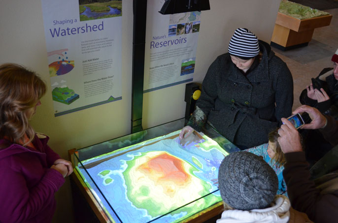 Visitors play with an augmented reality sandbox