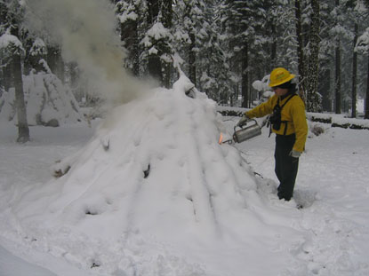 A park firefighter uses a drip torch to hand ignite a burn pile
