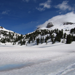lake helen is seen thawing out with lassen peak in the background.