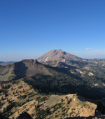 spine of dacite domes and remnants of old composite volcano with lassen peak in background and clear blue sky above.  As seen from Brokeoff Mountain