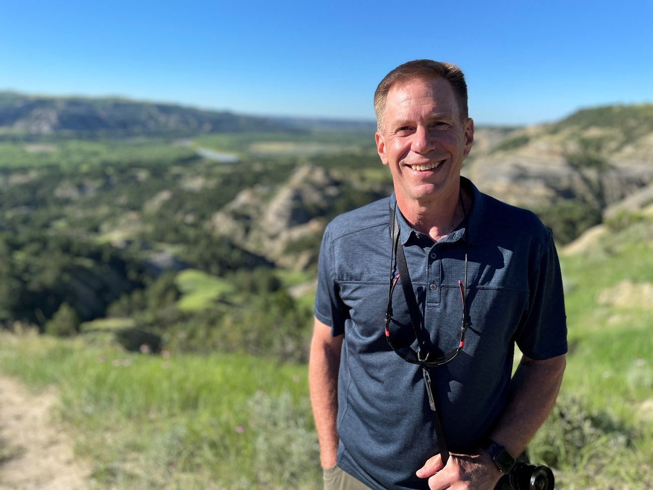 photo portrait of man smiling with rolling hills beyond