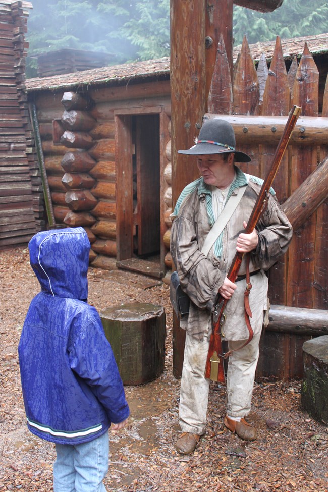 1805 costume ranger talking to a child in the rain.
