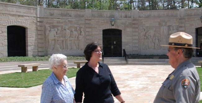 Park Ranger talking with two older women in front of limestone block building