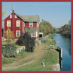 a frame house painted red, locaed along acourse of water