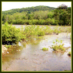 A wide stream with a low mountain inthe background