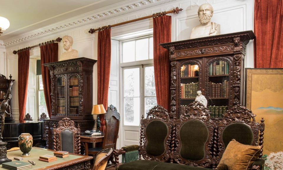Room with white walls, large windows, and several dark wood bookcases