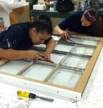 Two women repairing a window.