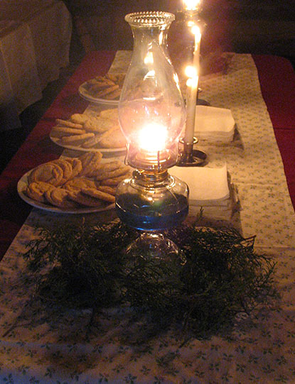 Table at the Johnson Cabin decorated with oil lamps and plates of cookies.