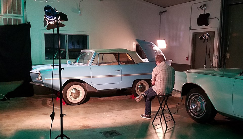 A videographer prepares lighting before filming President Johnson's amphibious car.