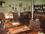 desks, stove, chalkboard in school room display