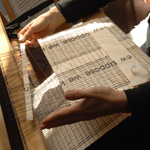 A close-up image of an artist's hands weaving wood and thread on her loom. NPS Photo.