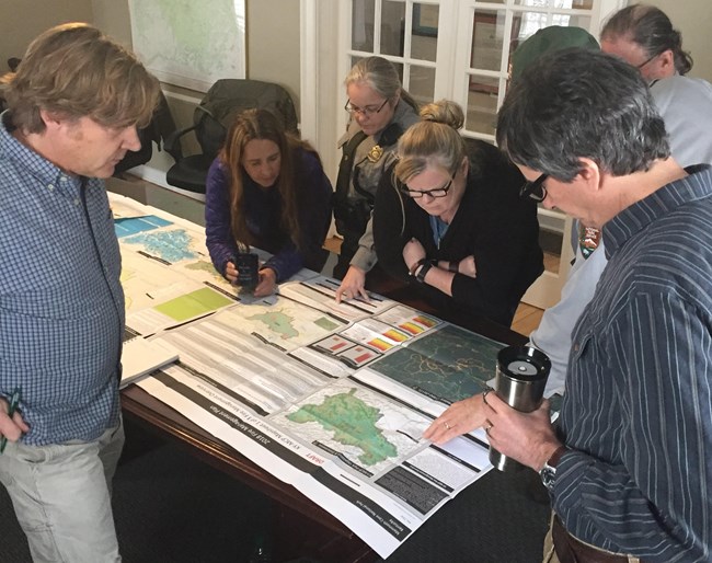 A group of people look at maps and plans on a table