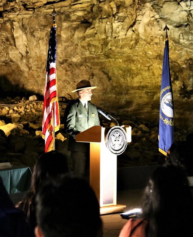 A park ranger giving a speech at a podium in the cave