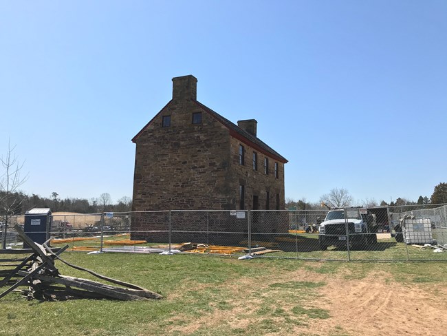 The Stone House at Manassas Battlefield surrounded by fences and work trucks.