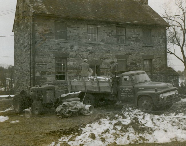 The stone house with workers and work vehicles during restoration in the 1950's