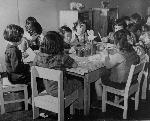 Children sit around a table doing arts and crafts