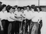 Smiling women gather around a softball bat