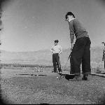 Young man lines up a shot while a friend looks on