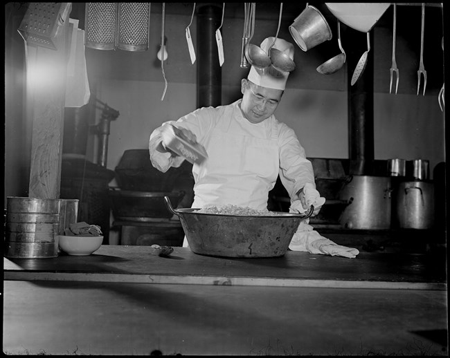 A black and white photo of a Japanese American chef at the camp.
