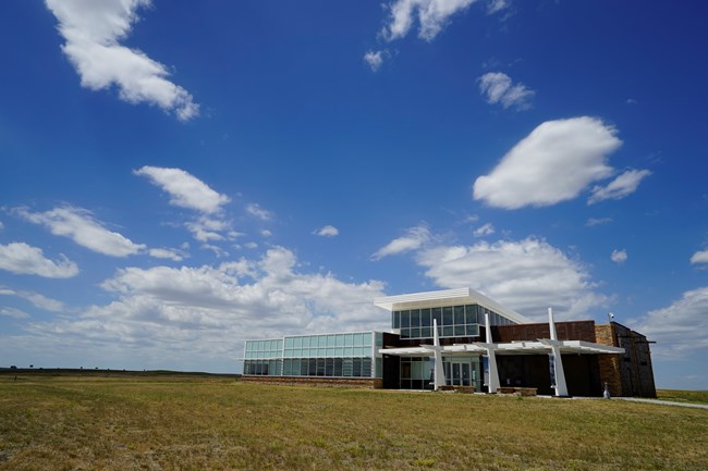 A large building rises above a prairie landscape