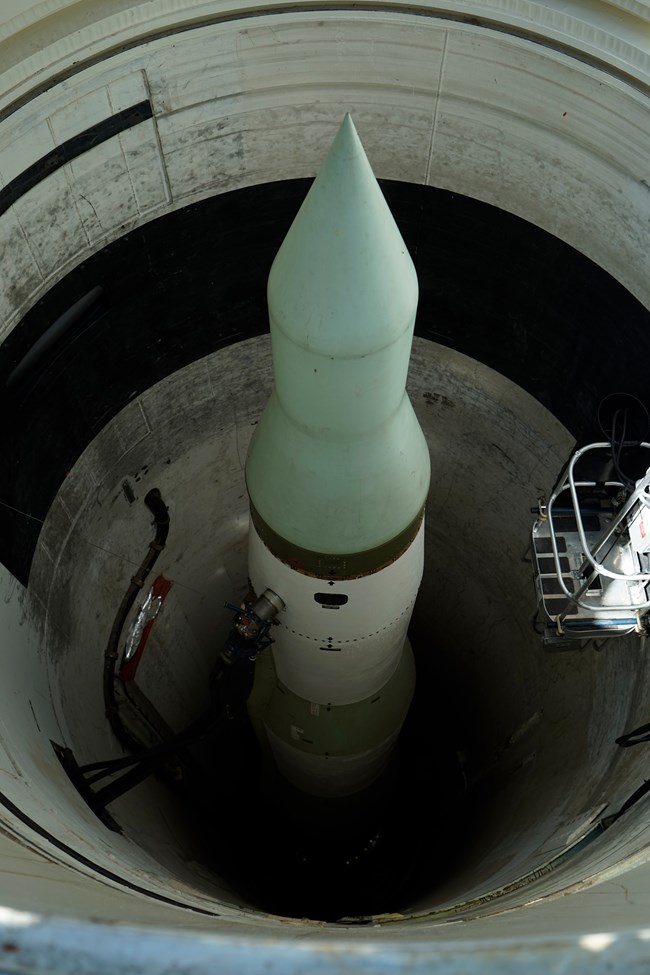 View down a cylindrical hole with a tall missile suspended inside it