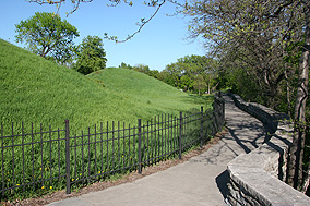 Large mounds beside a trail running through a semi-forested area.