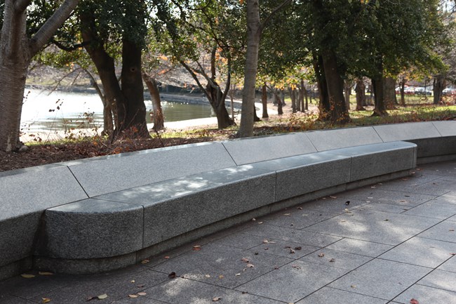 A concrete bench with no back or arm rests sits near the Martin Luther King, Jr. memorial