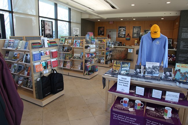 Books, pamphlets, and items are placed for sale inside of the bookstore. The checkout desk aligns the back wall.