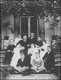 Large family seated on steps of a house.