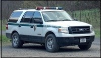 A white SUV with a green stripe and NPS arrowhead on side. A red and blue light bar on roof.