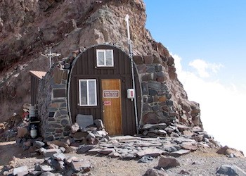 A small, half-domed building built out of rock and perched on a rocky ridge.