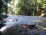 Water flows over and covers the roadway.