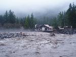 Brown churning river in front of building.