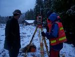 3 people stand around a surveyor's tripod