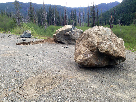 Boulders and damage on road surface.