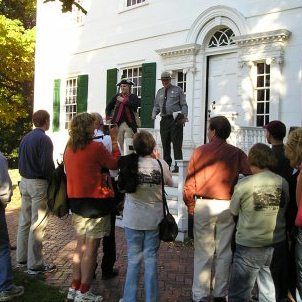 Visitors watching a park ranger present a tour on the steps of the Ford Mansion.  
