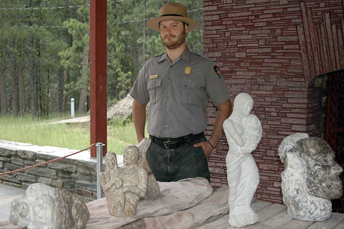 Artist in Residence Dustin Baker with some of his sculptures at Mount Rushmore.