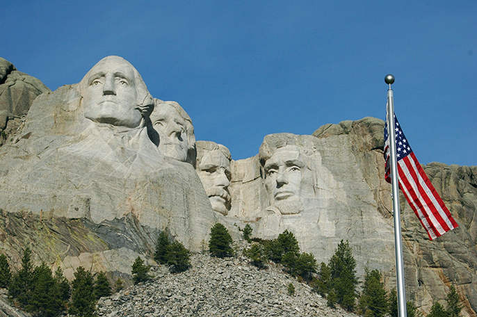 The United States flag flying in front of Mount Rushmore.