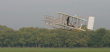 Replica of Wright Flyer III soaring above Huffman Prairie Flying Field.