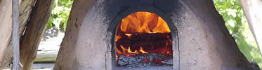 A wood fire glows in a clay Quebec oven outside the kitchen.