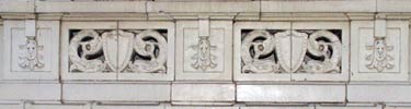 window detail, glazed terra cotta design, pair of two fish facing a shield with square ornamentation on either side