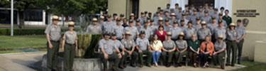 park employees, most in uniform, in front of adminstration building, standing on steps and around fountain