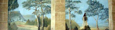 painted wall mural of scene of rolling hills with trees in the foreground and castle on the right side; border is painted faux stone