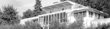 black and white photo of a flat roof house looking up from below
