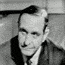 Still photo of Mike Wallace interview with Orval Faubus, 1957. Faubus is in a suit and tie, sitting behind desk in governor's office.