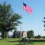 cannon on old military parade grounds with flag flying and Commissary in distance