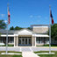 Main entrance to the yellow-brick Presidential Library and Museum, with columns and US flags.